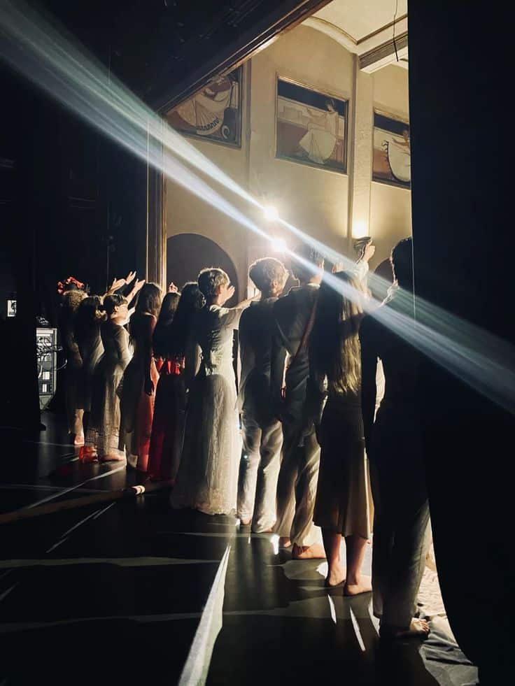 theatre aesthetic Backstage view of performers lined up, in elegant costumes, ready to take the stage under dramatic lighting. | Sky Rye Design Backstage view of performers lined up, in elegant costumes, ready to take the stage under dramatic lighting.