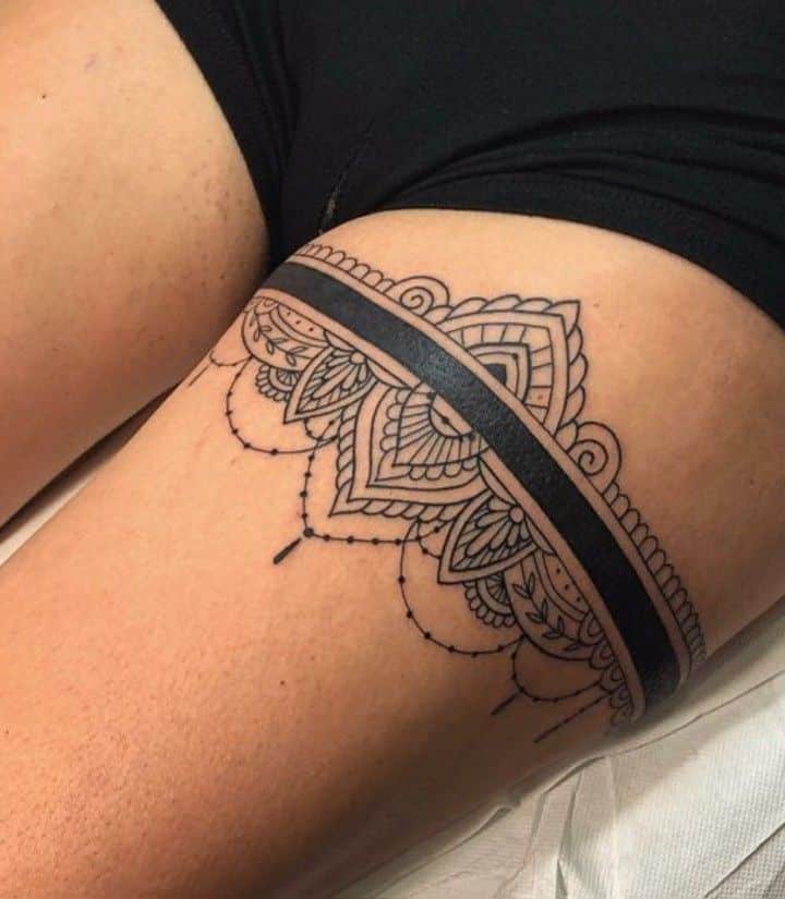 _ Intricate black lace garter thigh tattoo with geometric and floral patterns, elegantly designed around the upper thigh area. | Sky Rye Design Intricate black lace garter thigh tattoo with geometric and floral patterns, elegantly designed around the upper thigh area.