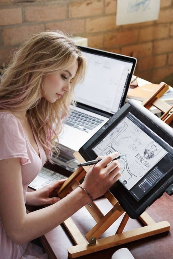 _ Woman using a digital drawing tablet with a stylus at a desk, focused on creating a detailed sketch, enhancing digital creativity. | Sky Rye Design Woman using a digital drawing tablet with a stylus at a desk, focused on creating a detailed sketch, enhancing digital creativity.