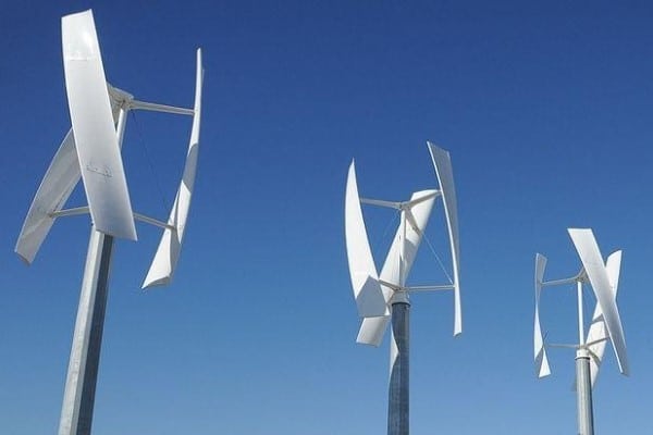 Three vertical axis wind turbines against a clear blue sky, generating renewable energy efficiently and sustainably.
