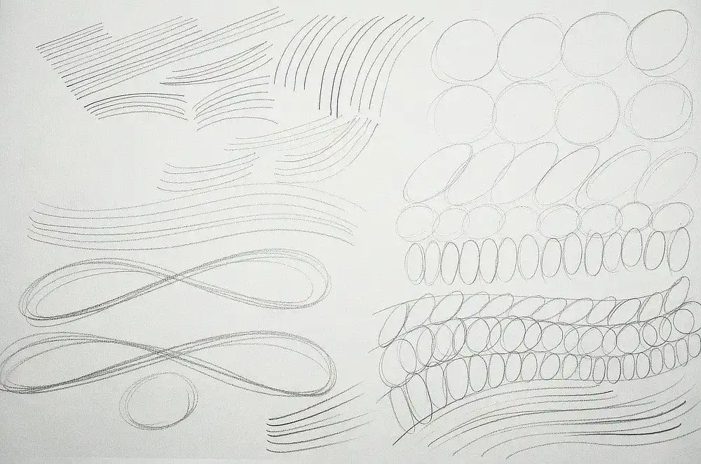 Various pencil sketches of lines, loops, and circles on paper for drawing practice, focusing on improving hand control and precision.