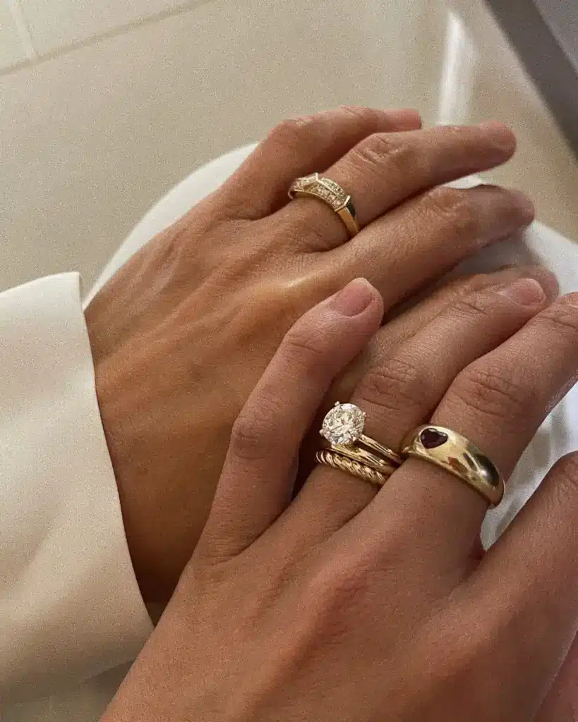 weddingband_holding_01 Hands with elegant gold rings featuring gemstones and diamonds, symbolizing commitment and love. Close-up shot of wedding jewelry. | Sky Rye Design Hands with elegant gold rings featuring gemstones and diamonds, symbolizing commitment and love. Close-up shot of wedding jewelry.