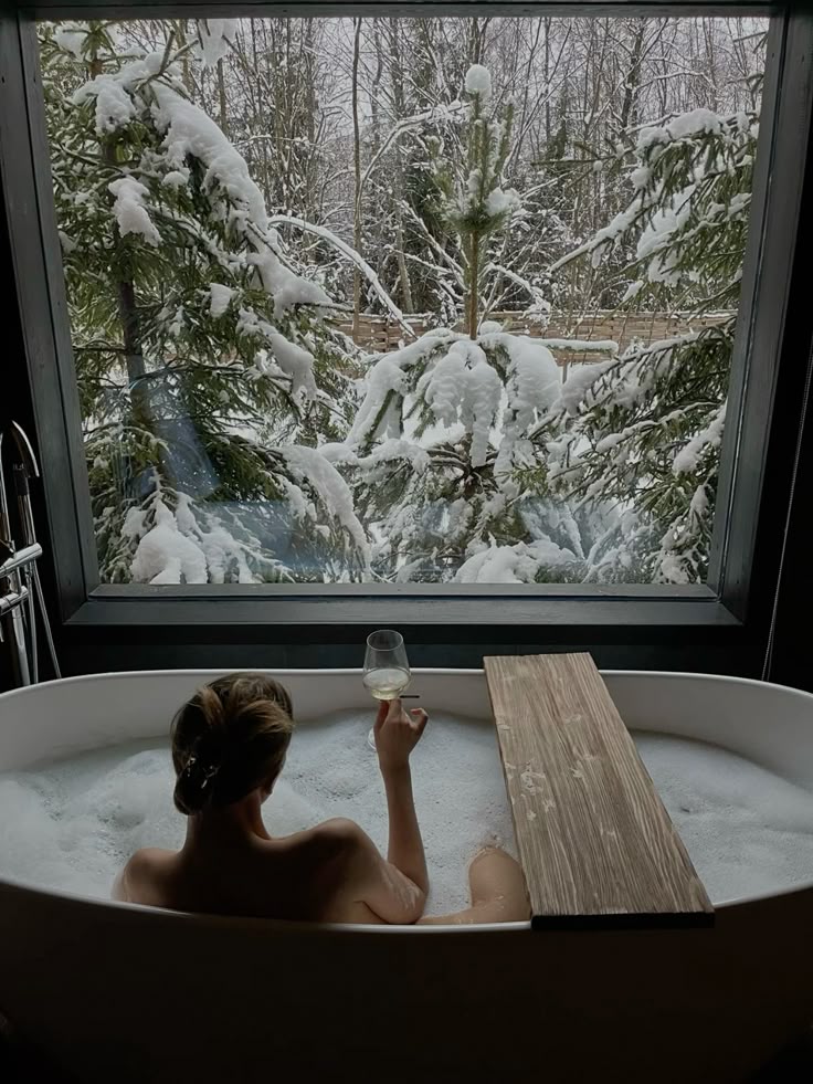 Зимняя сказка Woman relaxing in a bathtub with a glass of wine, enjoying a snowy forest view through a large window. | Sky Rye Design Woman relaxing in a bathtub with a glass of wine, enjoying a snowy forest view through a large window.