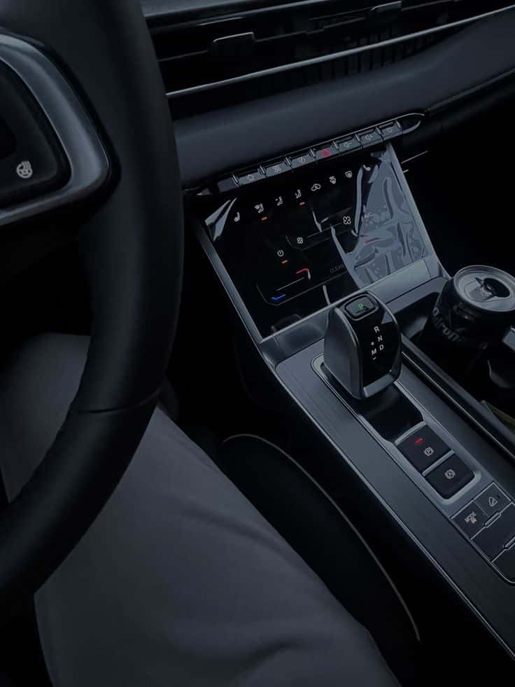 Close-up of a modern car interior featuring a sleek gear shifter and digital controls, highlighting advanced automotive technology.