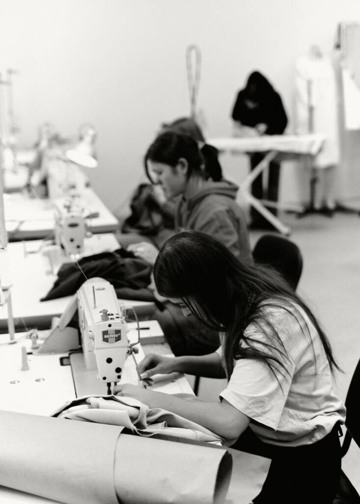 People working intently on sewing machines in a garment workshop, crafting textiles and clothing with precision and skill.