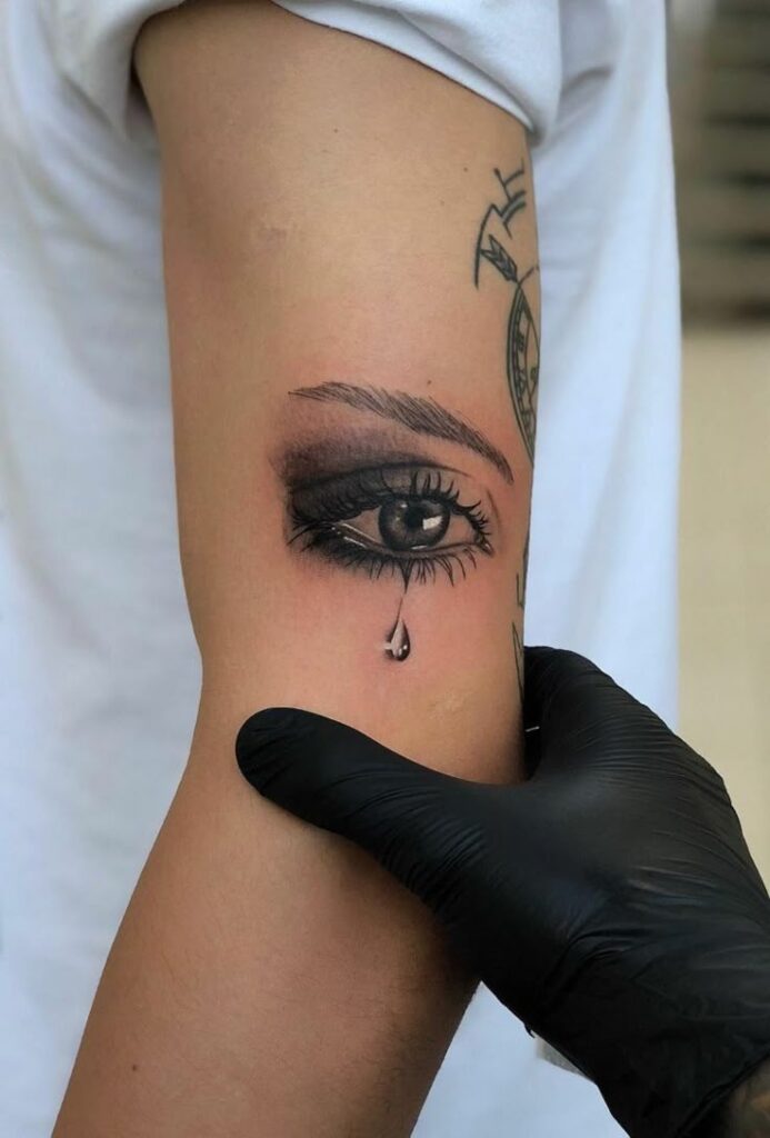 ▷ 1001 + Idee per Tatuaggio occhio per uomo e donna Tattoo of a realistic eye with teardrop on forearm, black glove adjusting arm position, artistic ink design, creativity and expression. | Sky Rye Design Tattoo of a realistic eye with teardrop on forearm, black glove adjusting arm position, artistic ink design, creativity and expression.