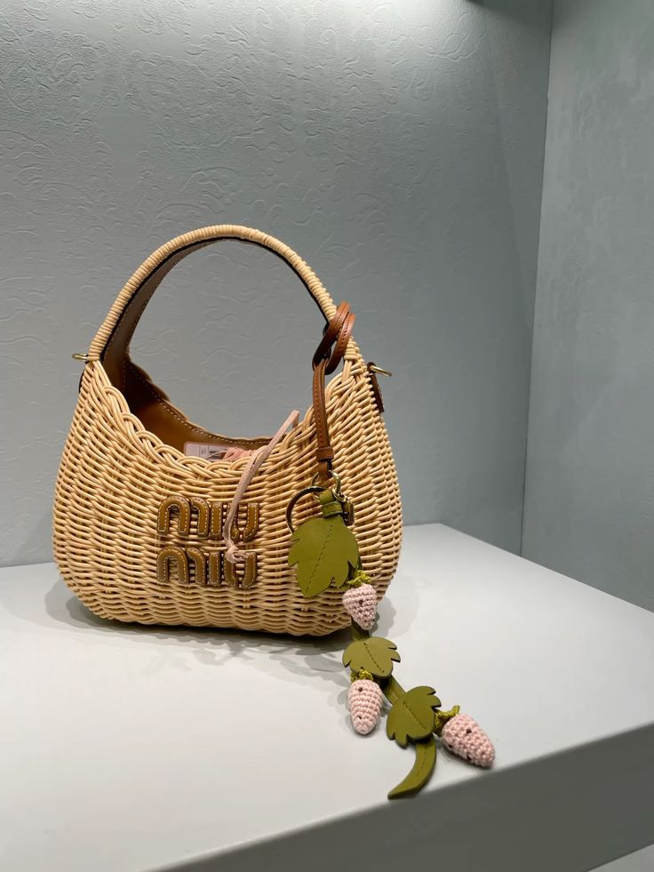 🤎 Fashionable wicker handbag with leather strap and decorative charm, displayed on a white shelf, perfect for summer style enthusiasts. | Sky Rye Design Fashionable wicker handbag with leather strap and decorative charm, displayed on a white shelf, perfect for summer style enthusiasts.