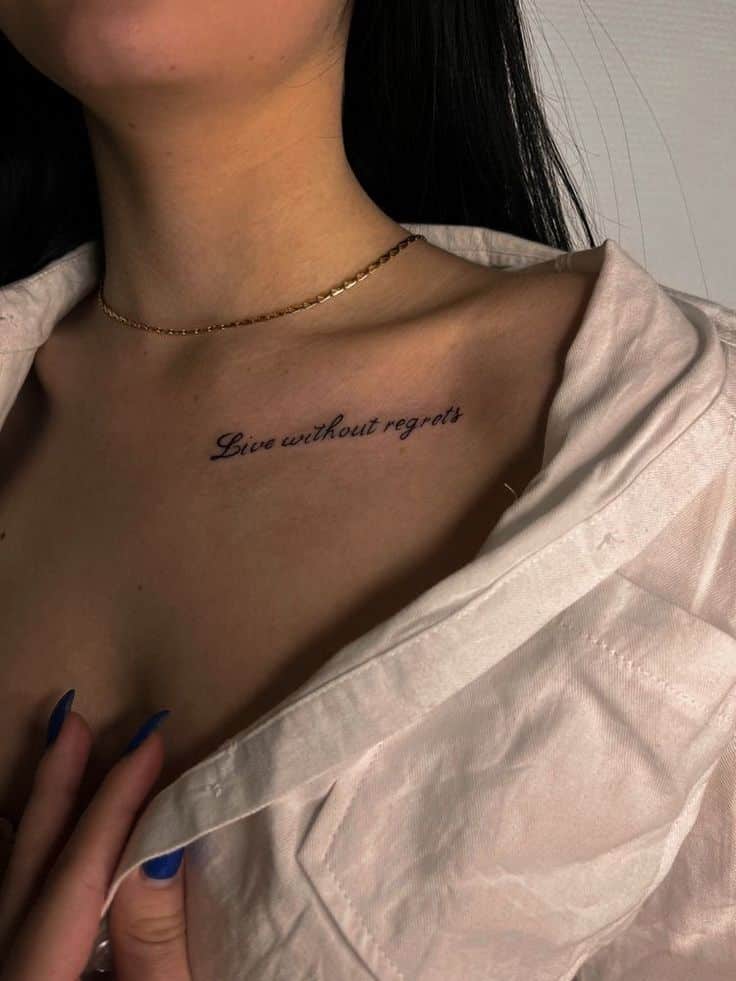 079e4dc1-0132-4d2f-bca0-04bbe88ab6d4 Woman with a Live without regrets tattoo on collarbone, wearing a white shirt and gold necklace. | Sky Rye Design Woman with a Live without regrets tattoo on collarbone, wearing a white shirt and gold necklace.