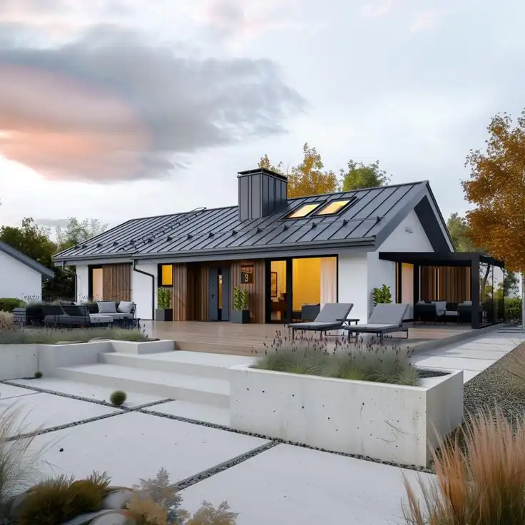 Modern single-story house with a sleek black roof, large windows, and a spacious patio, surrounded by autumn trees at sunset.