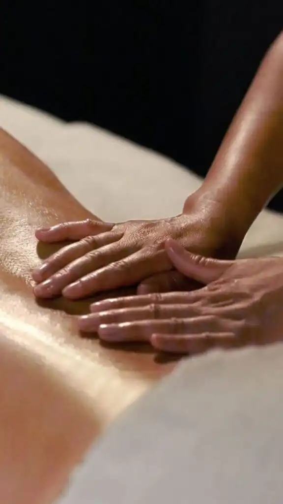 Massage therapist performing relaxing back massage therapy, hands applying oil for wellness and stress relief.