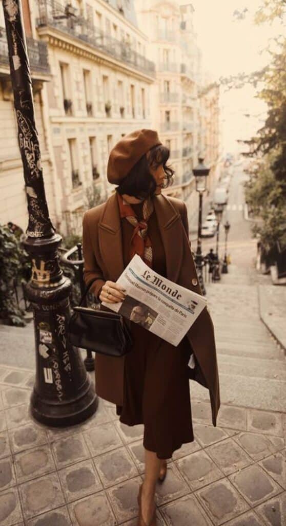 10 outfits elegantes con abrigo perfectos para otoño-invierno 2021 Stylish woman in brown outfit and beret walks down Parisian steps holding a newspaper, embodying chic autumn fashion vibes. | Sky Rye Design Stylish woman in brown outfit and beret walks down Parisian steps holding a newspaper, embodying chic autumn fashion vibes.