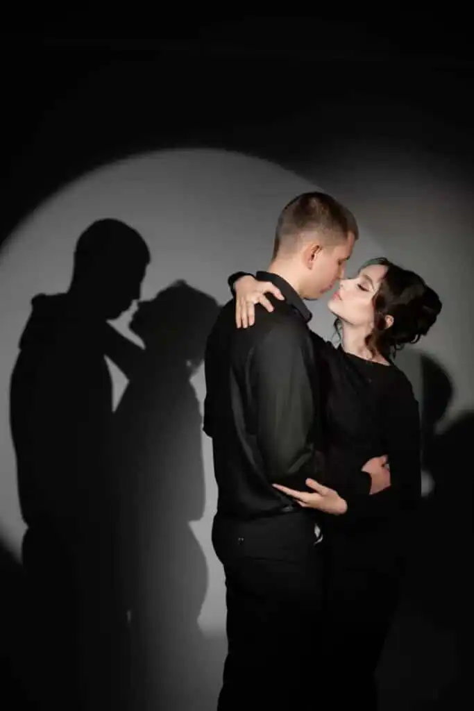 _ 11 Couple embracing in a spotlight, casting romantic shadows on the wall behind them. | Sky Rye Design Couple embracing in a spotlight, casting romantic shadows on the wall behind them.