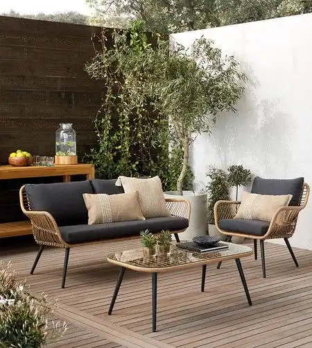 Outdoor patio with stylish wicker furniture, cushions, and a glass table, surrounded by greenery and wooden decor for a
