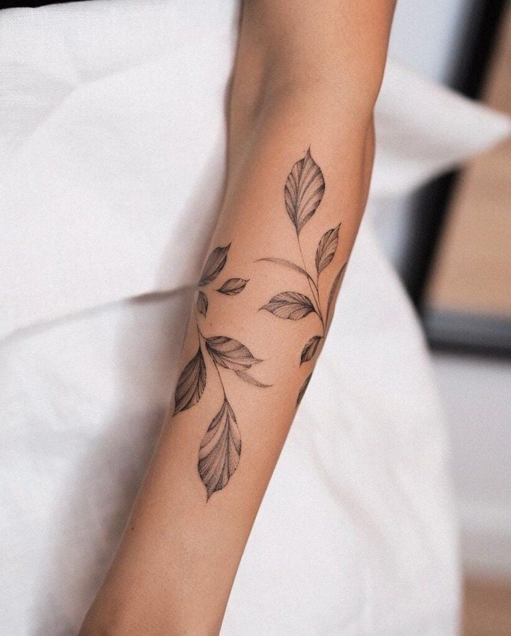 Elegant forearm tattoo featuring delicate line art leaves, highlighting minimalist and nature-inspired body art designs.