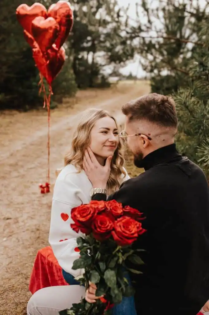 _ 15 Couple sharing a romantic moment in a forest with red roses and heart-shaped balloons, expressing love and affection. | Sky Rye Design Couple sharing a romantic moment in a forest with red roses and heart-shaped balloons, expressing love and affection. Valentine's Day Photography