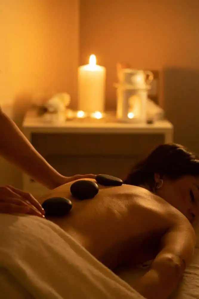 Woman enjoying a relaxing hot stone massage in a cozy, candlelit spa setting for soothing relaxation and stress relief.