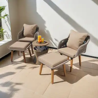 Outdoor seating set with beige cushions, two armchairs, and small table with fruit and drinks. Sunlit patio with modern