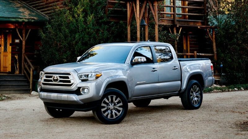 2021ToyotaTacoma-exterior-03 Silver pickup truck parked in front of a rustic log cabin surrounded by greenery and trees, showcasing outdoor adventure readiness. | Sky Rye Design Silver pickup truck parked in front of a rustic log cabin surrounded by greenery and trees, showcasing outdoor adventure readiness.