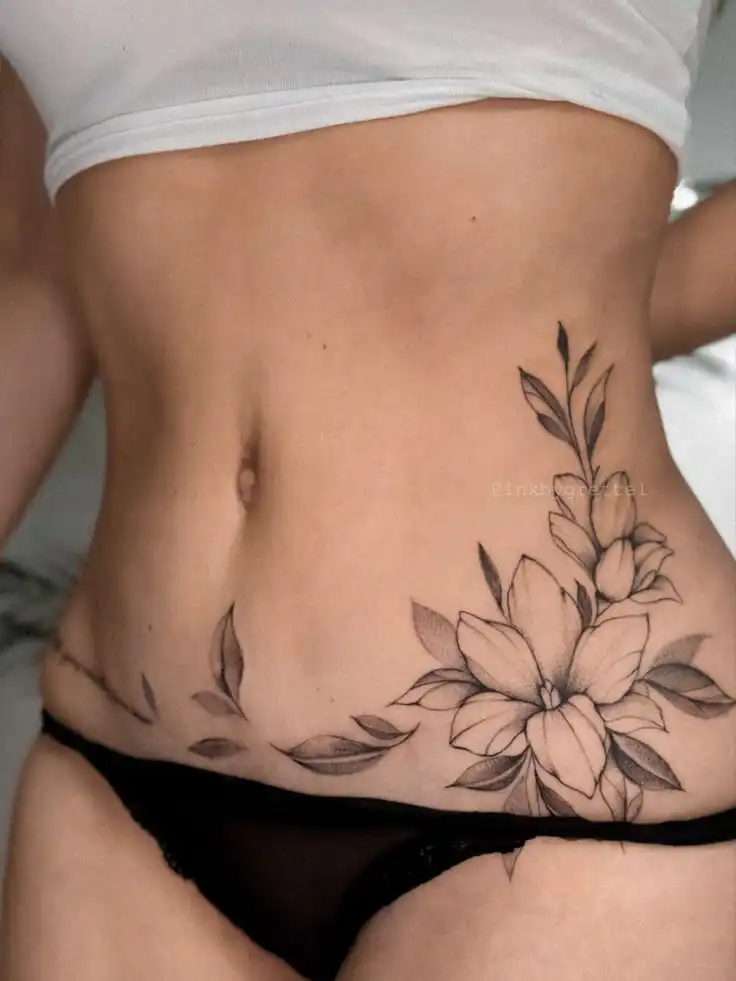 _ - 2026-01-04T192642788 Close-up of a woman's lower abdomen featuring intricate black and grey floral tattoo designs. | Sky Rye Design Close-up of a woman's lower abdomen featuring intricate black and grey floral tattoo designs.