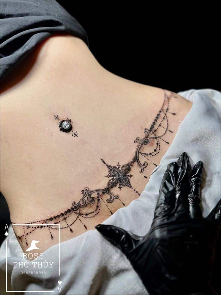 _ - 2026-01-04T192705074 Elegant chest tattoo design with ornamental details and a black gemstone. Tattoo artist wearing black gloves. | Sky Rye Design Elegant chest tattoo design with ornamental details and a black gemstone. Tattoo artist wearing black gloves.