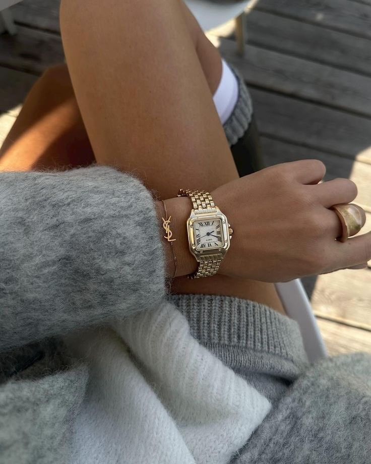 Stylish woman wearing a gold bracelet watch with a fuzzy gray sweater, showcasing elegant fashion and accessories on a cozy day. Trendy Accessories in 2026