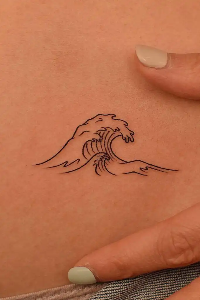 25 Simple Wave Tattoo Ideas Minimalist wave tattoo on skin, depicting a simple, elegant ocean wave design with a hand gently pointing near it. | Sky Rye Design Minimalist wave tattoo on skin, depicting a simple, elegant ocean wave design with a hand gently pointing near it.