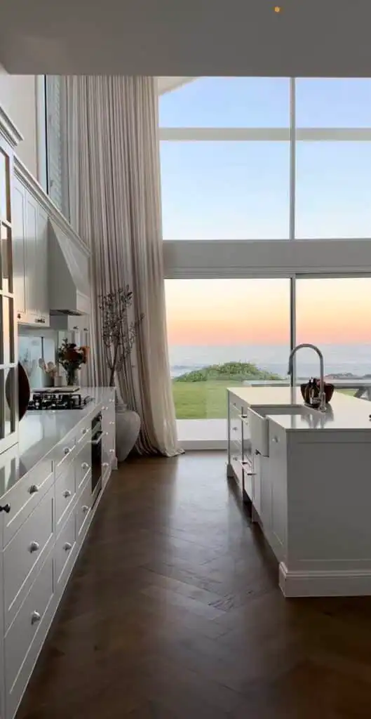 _ 26 Modern kitchen with large windows, white cabinets, and ocean view at sunset, creating a serene and elegant cooking space. | Sky Rye Design Modern kitchen with large windows, white cabinets, and ocean view at sunset, creating a serene and elegant cooking space.
