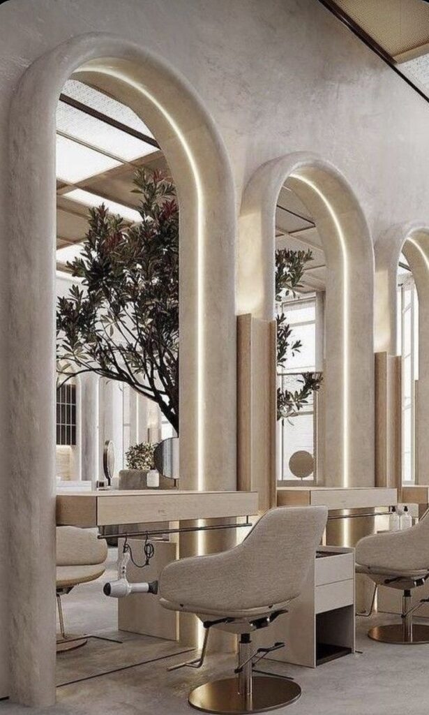 Screenshot Stylish modern salon interior with elegant arch mirrors, beige chairs, and underlit decor creating a chic, luxurious atmosphere. | Sky Rye Design Stylish modern salon interior with elegant arch mirrors, beige chairs, and underlit decor creating a chic, luxurious atmosphere.