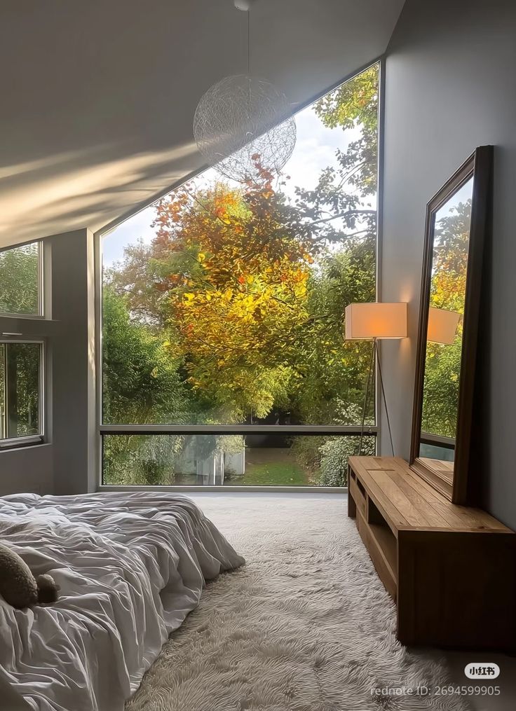 _ 30 Modern bedroom with large windows and a view of fall foliage. Cozy bedding, wood furniture, and natural light create a serene atmosphere. | Sky Rye Design Modern bedroom with large windows and a view of fall foliage. Cozy bedding, wood furniture, and natural light create a serene atmosphere. Big Windows