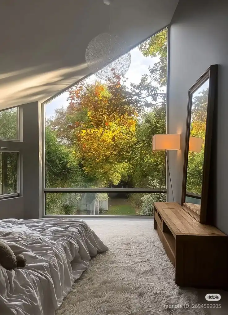 _ 30 Modern bedroom with large windows and a view of fall foliage. Cozy bedding, wood furniture, and natural light create a serene atmosphere. | Sky Rye Design Modern bedroom with large windows and a view of fall foliage. Cozy bedding, wood furniture, and natural light create a serene atmosphere. Big Windows