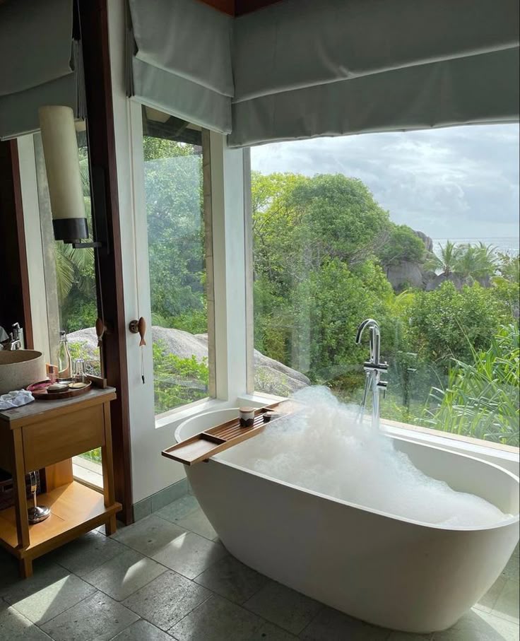 _ 34 Luxurious bathtub with bubbles by a window overlooking lush greenery, offering a serene and relaxing bathroom experience. | Sky Rye Design Luxurious bathtub with bubbles by a window overlooking lush greenery, offering a serene and relaxing bathroom experience.