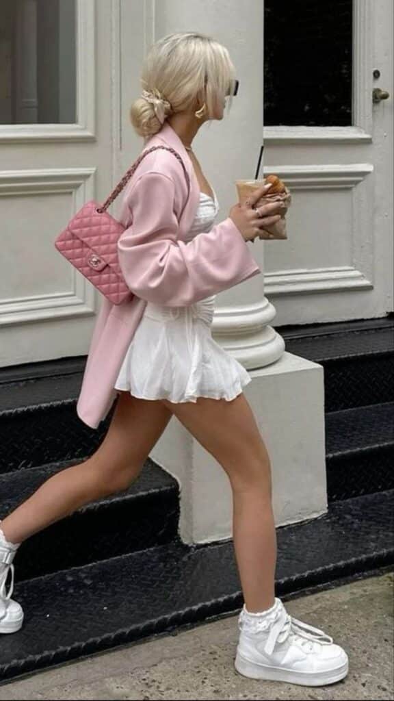 _ 38 Woman in stylish white dress with pink jacket and handbag, walking on the street holding iced coffee, wearing white sneakers. | Sky Rye Design Woman in stylish white dress with pink jacket and handbag, walking on the street holding iced coffee, wearing white sneakers.