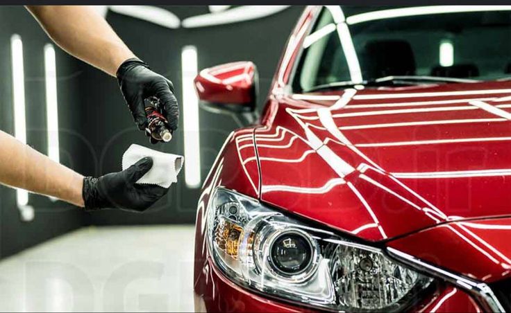_ 4 Person applying ceramic coating to red car's headlight, enhancing shine and protection in a professional detailing garage. | Sky Rye Design Person applying ceramic coating to red car's headlight, enhancing shine and protection in a professional detailing garage.