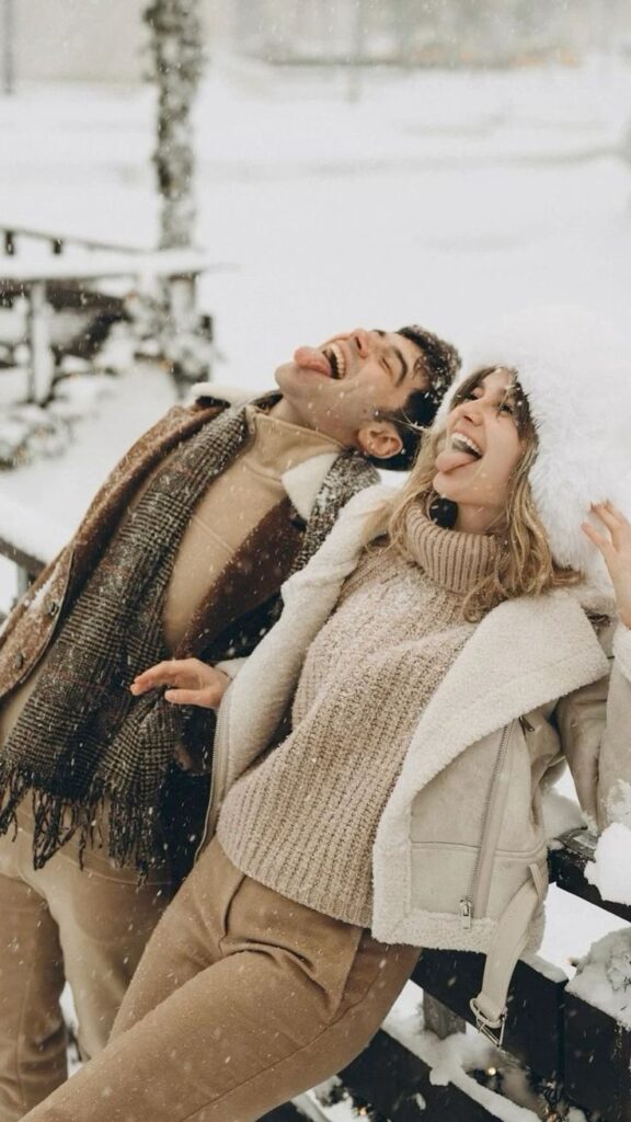 _ 4 Couple enjoying a snowy day, catching snowflakes on their tongues while dressed warmly in winter attire. | Sky Rye Design Couple enjoying a snowy day, catching snowflakes on their tongues while dressed warmly in winter attire.