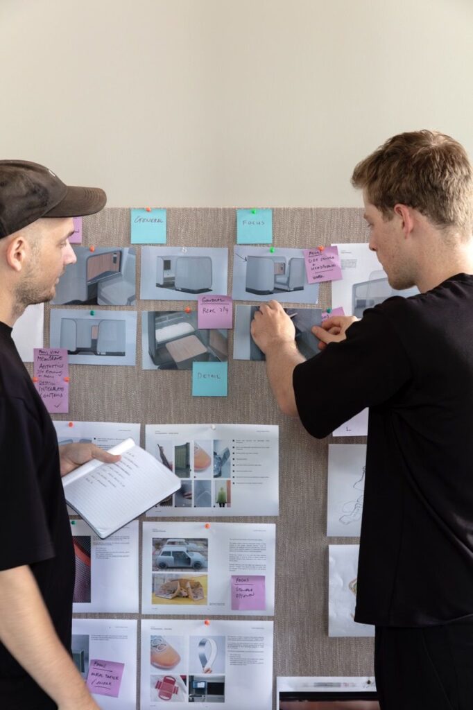 452bf0fccaca137963574d9a6d982dc4 Two designers collaborating, reviewing product concepts on a wall board with notes and sketches, enhancing creative planning and strategy. | Sky Rye Design Two designers collaborating, reviewing product concepts on a wall board with notes and sketches, enhancing creative planning and strategy.