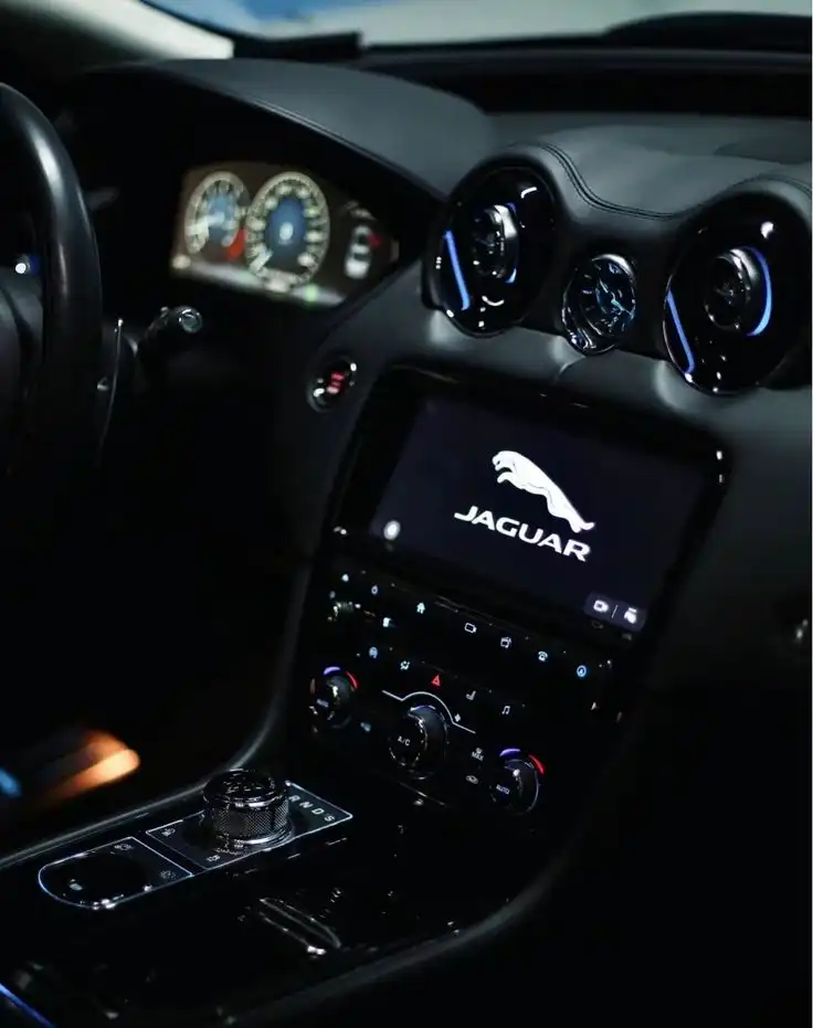 Luxury car interior with high-tech dashboard featuring Jaguar logo, ambient lighting, and precision controls for a sleek