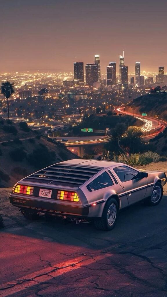 Retro car overlooking a city skyline at dusk, with glowing city lights in the background and winding roads below.