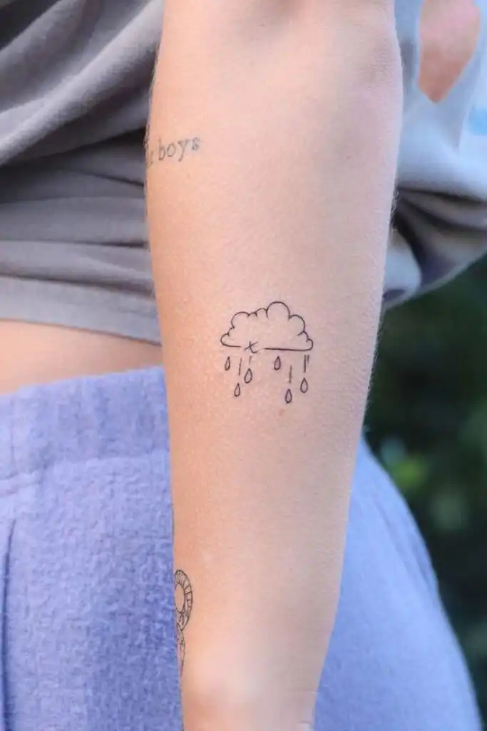 51 Unbelievable Pretty Simple Tattoos To Decorate Your Body With Minimalist cloud and rain tattoo on forearm, showcasing small and delicate design in black ink. | Sky Rye Design Minimalist cloud and rain tattoo on forearm, showcasing small and delicate design in black ink.