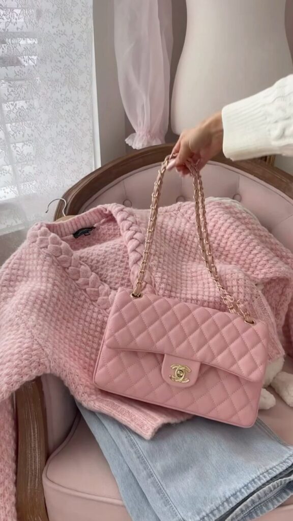_ 56 Pink quilted handbag on textured pink sweater and blue jeans, placed on a chair. Elegant and stylish accessory arrangement. | Sky Rye Design Pink quilted handbag on textured pink sweater and blue jeans, placed on a chair. Elegant and stylish accessory arrangement.