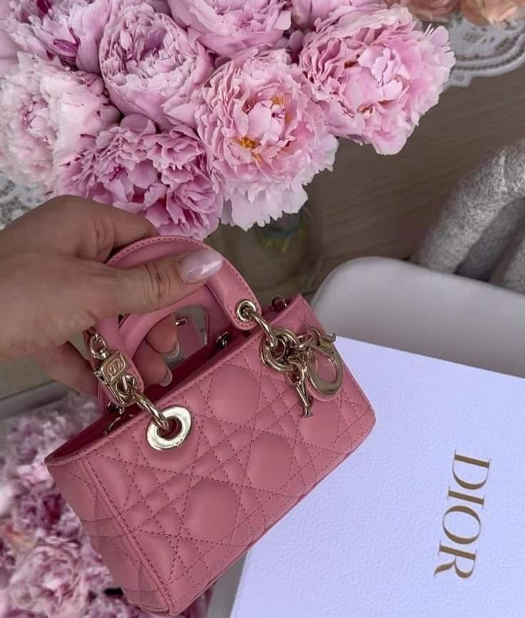 _ 57 Pink designer handbag held above a bouquet of pink peonies, next to a luxury brand box. | Sky Rye Design Pink designer handbag held above a bouquet of pink peonies, next to a luxury brand box.