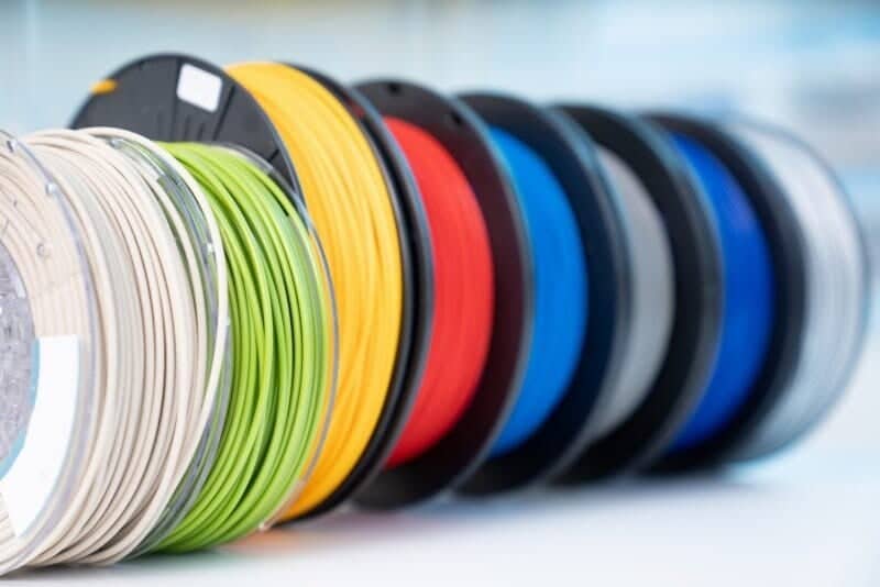 Colorful 3D printer filament spools in a row, showcasing a range of vibrant colors for versatile 3D printing projects.