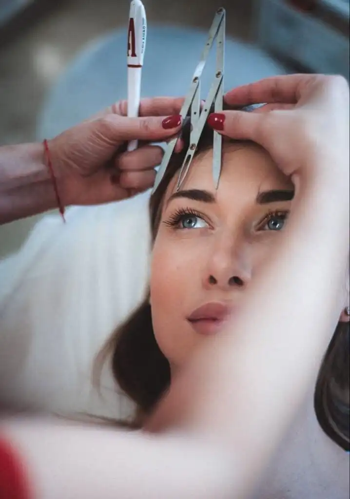 _ 6 Woman receiving eyebrow measurement for shaping with calipers, close-up on face and tool, beauty salon setting. | Sky Rye Design Woman receiving eyebrow measurement for shaping with calipers, close-up on face and tool, beauty salon setting.