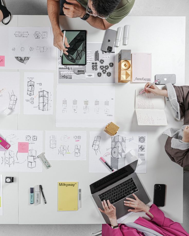 60286f60250443bb2e4d3cb59e7a7ae6 Aerial view of a creative workspace with design sketches, a tablet, and a laptop, showcasing teamwork and innovation in product development. | Sky Rye Design Aerial view of a creative workspace with design sketches, a tablet, and a laptop, showcasing teamwork and innovation in product development.