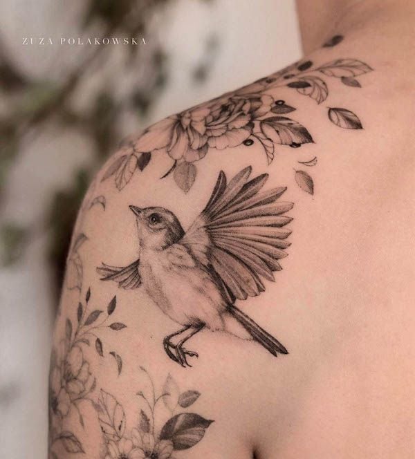 Detailed bird and floral tattoo on shoulder, showcasing intricate line work and artistic design.