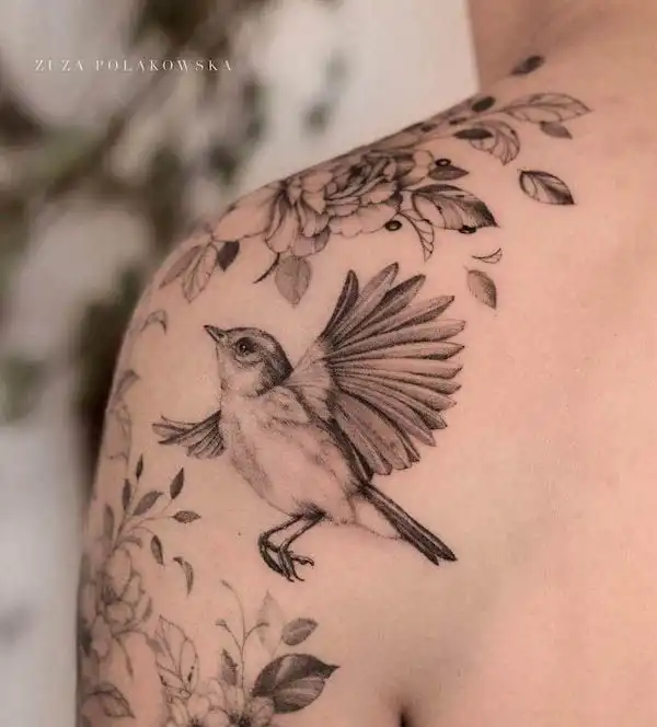 Detailed bird and floral tattoo on shoulder, showcasing intricate line work and artistic design.