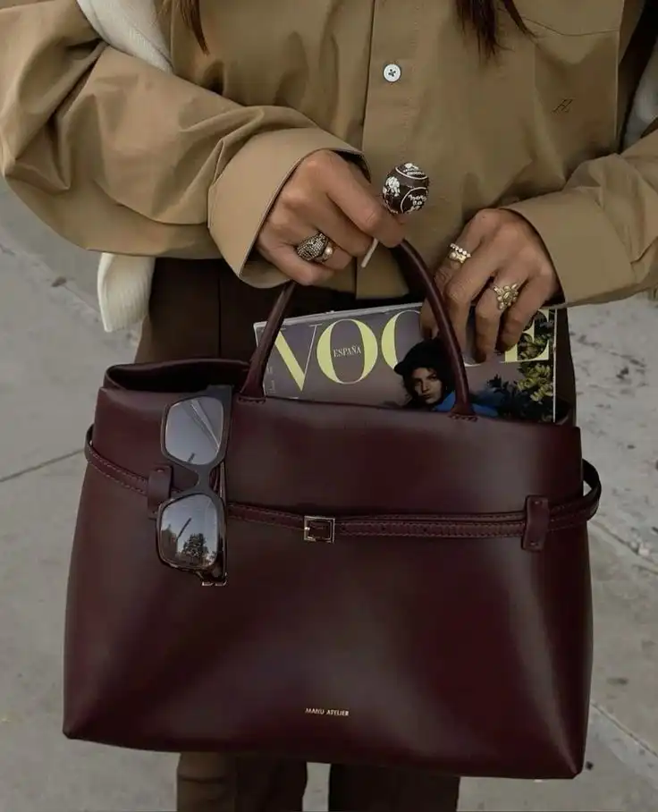 Stylish outfit with a brown handbag, sunglasses, and Vogue magazine. Perfect for fashion lovers. Sophisticated and elegant accessories.