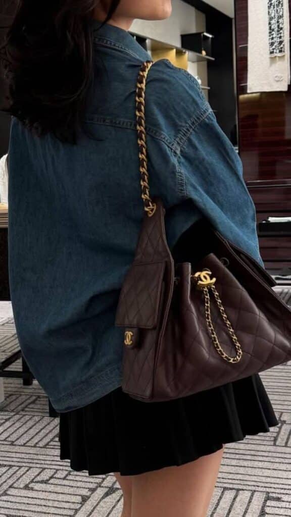 _ 74 Stylish woman in denim jacket carrying a quilted designer handbag with gold chain in upscale setting. Fashion and elegance combine. | Sky Rye Design Stylish woman in denim jacket carrying a quilted designer handbag with gold chain in upscale setting. Fashion and elegance combine.