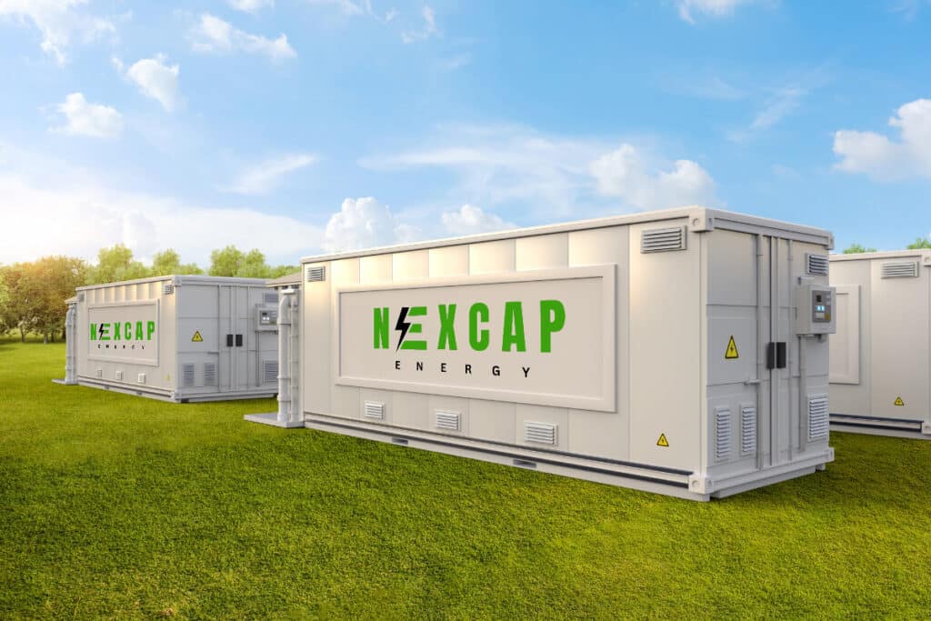 Battery storage units by NEXCAP Energy on a grassy field under a blue sky, showcasing sustainable energy solutions.