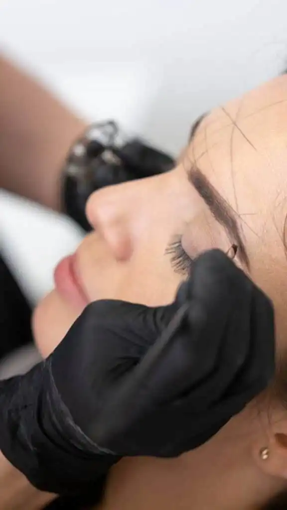 _ 8 Beautician applying eyebrow treatment with black gloves in a cosmetic procedure, close-up on closed eyes and precise work. | Sky Rye Design Beautician applying eyebrow treatment with black gloves in a cosmetic procedure, close-up on closed eyes and precise work.