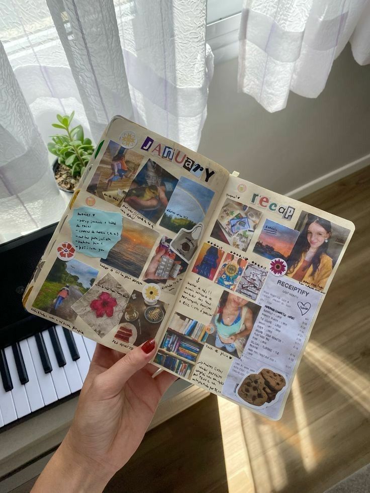 _ 88 Open scrapbook displaying a creative January recap with photos, stickers, and handwritten notes, held above a piano near sunlight. | Sky Rye Design Open scrapbook displaying a creative January recap with photos, stickers, and handwritten notes, held above a piano near sunlight.